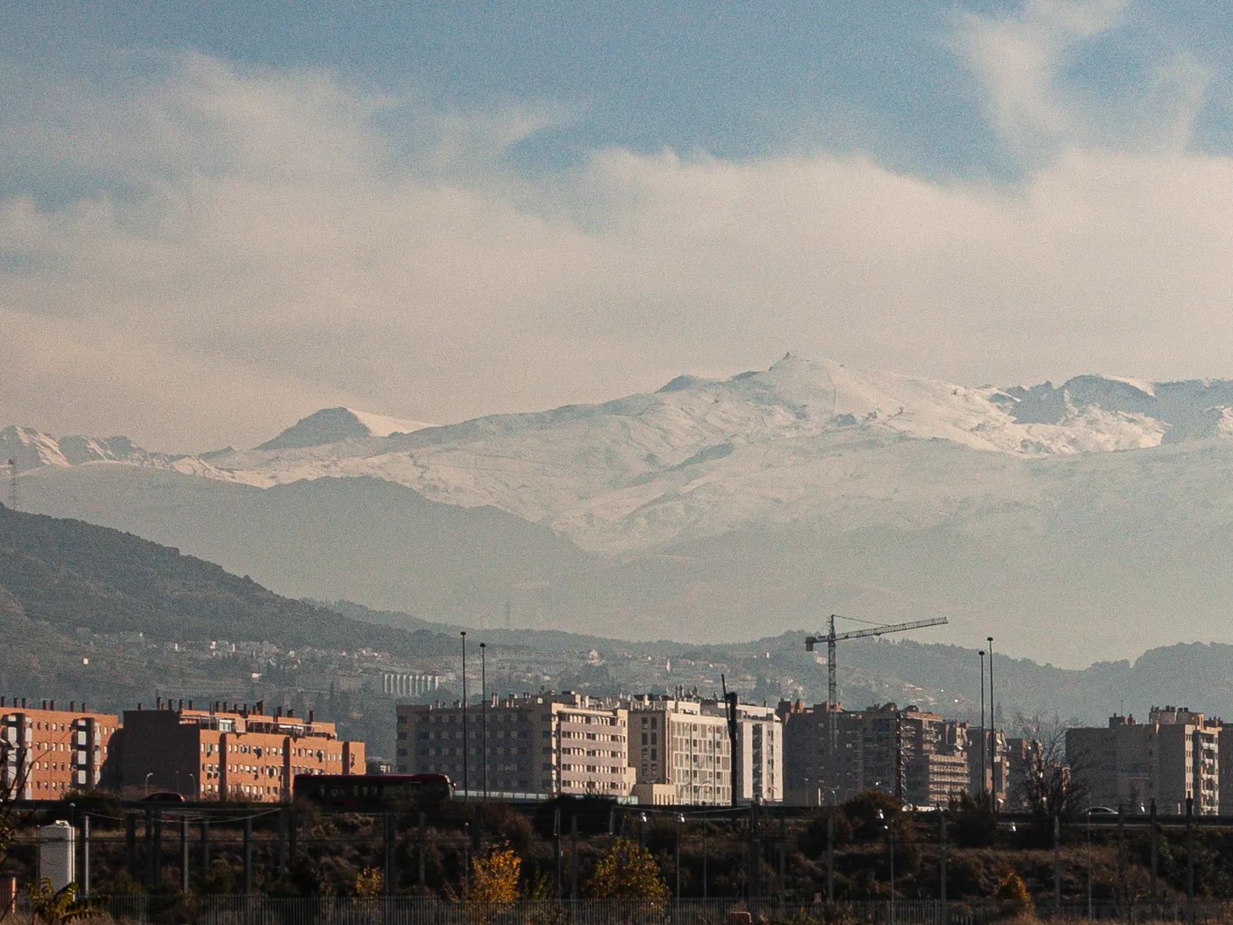 Granada city skyline with the majestic snow-capped Sierra Nevada mountains in the background.