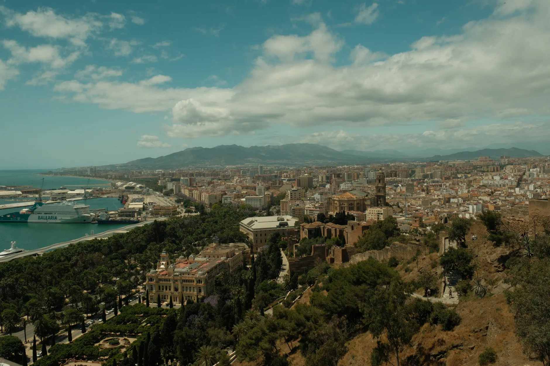 Aerial view of Malaga city, showcasing the harbor and cityscape under a cloudy sky.